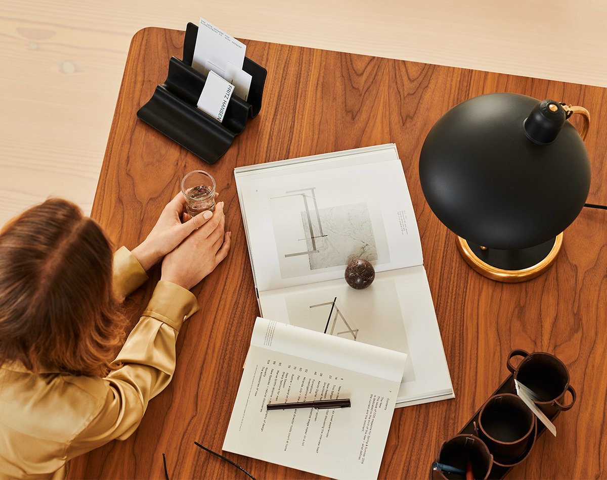 mulher em uma mesa com caderno e luminária KAISER Idell Luxus vista de cima