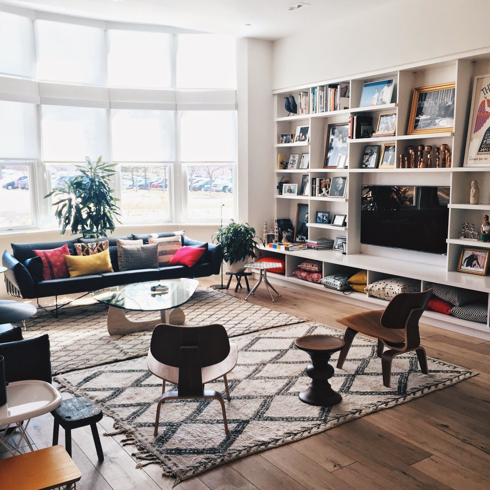 Ambiente Eames: sala com sofás, cadeiras e estante com livros.
