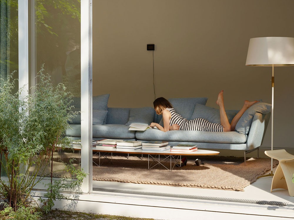 Atec ambiente Eames: mulher deitada em sofá lendo um livro