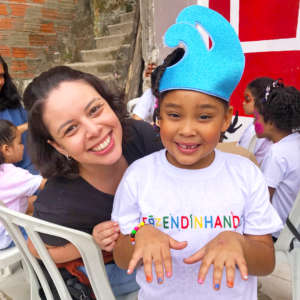 Foto de voluntária com criança de unhas pintadas.